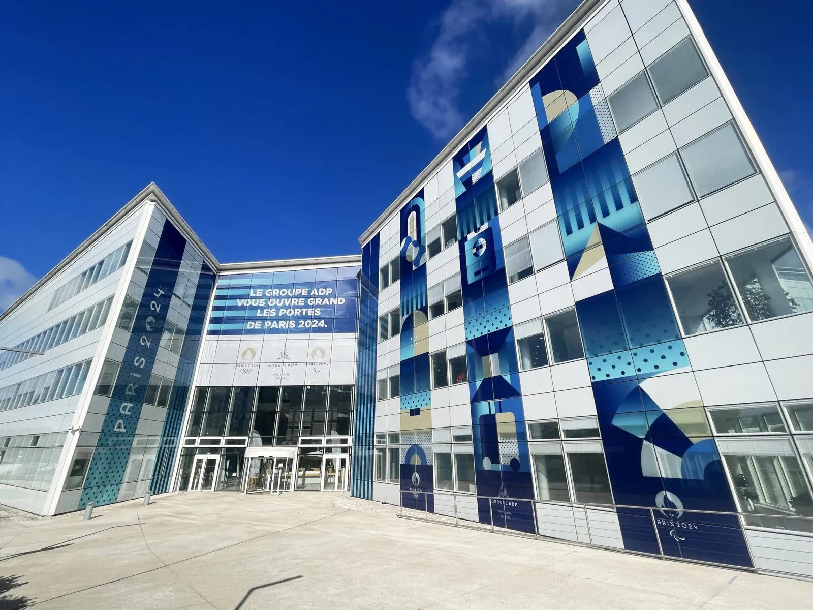 Façade vitrée d'un immeuble de bureaux habillée de visuels adhésifs grand format, réalisation SORA