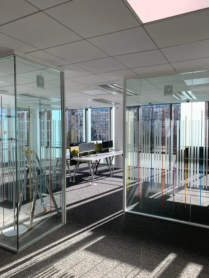 Couloir de bureaux bordé de cloisons vitrées avec bande dépolie continue