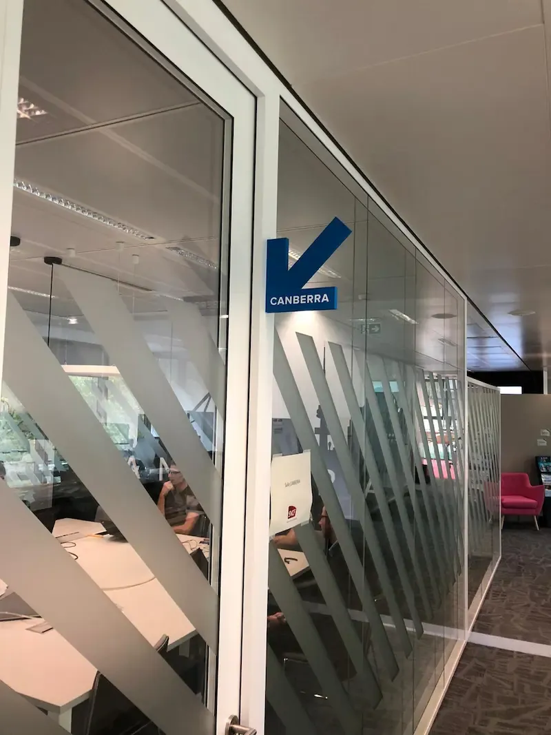 Porte vitrée de bureau avec flèche signalétique bleue et bandes diagonales dépolies