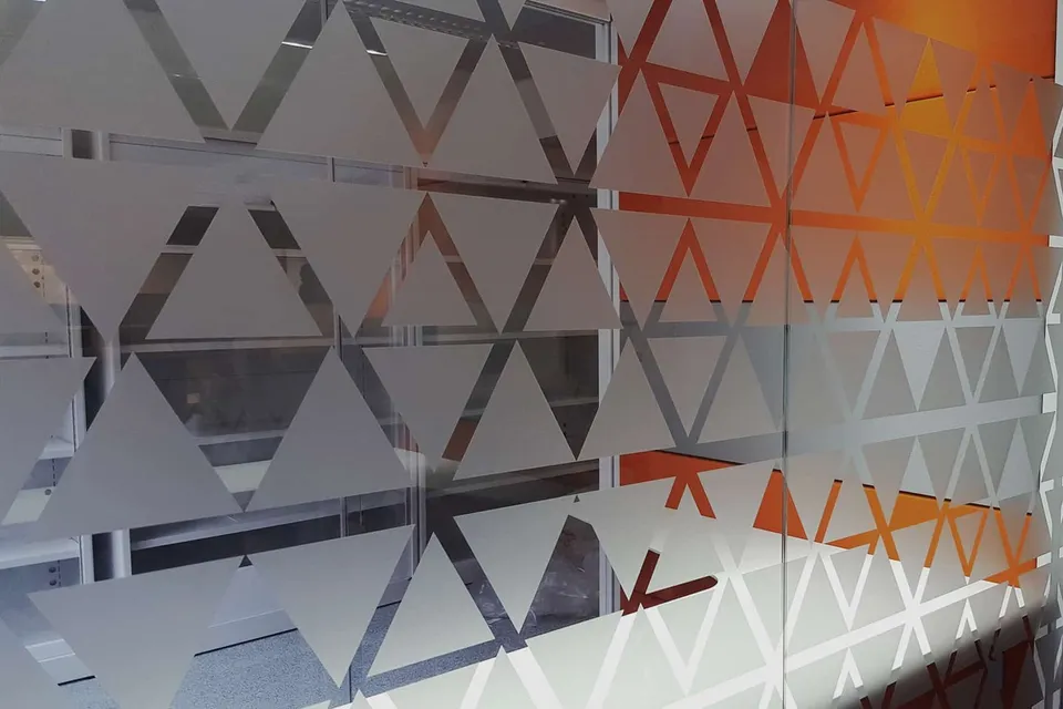 Cloison vitrée habillée d'un motif géométrique de triangles orange et dépolis