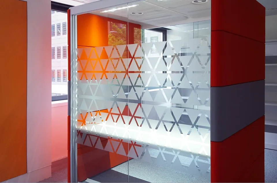 Salle de réunion vitrée avec bande de triangles orange et dépolis